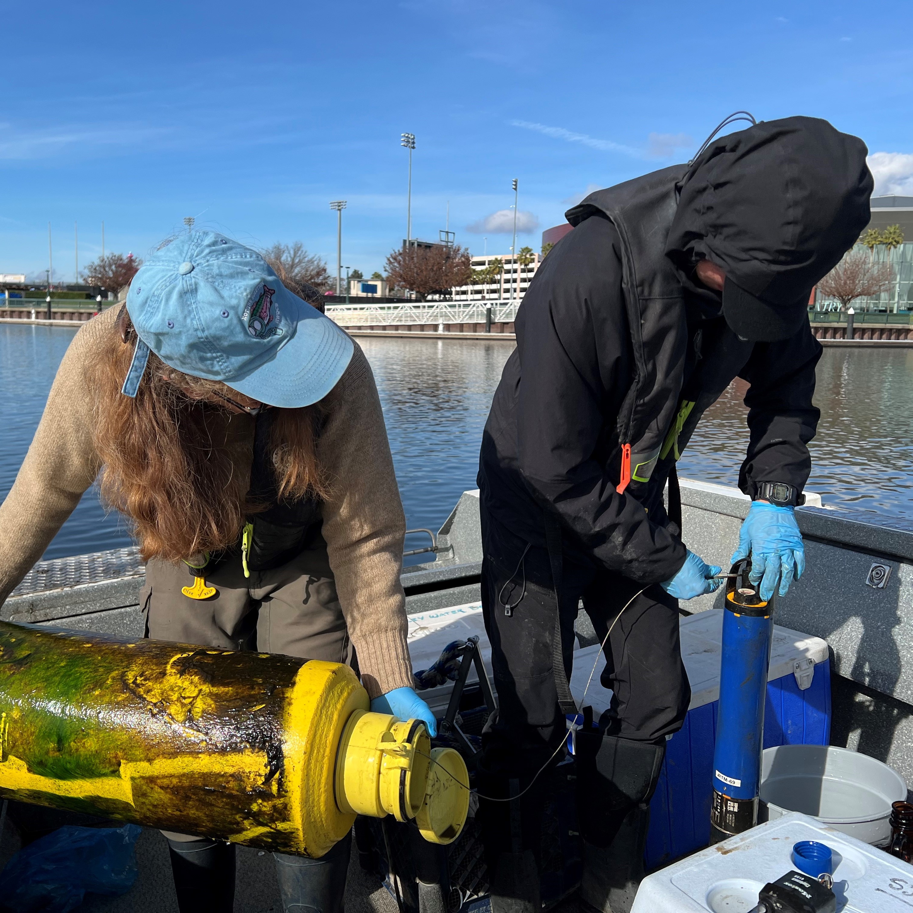 Photograph of two people on a boat preparing a sonde for deployment.