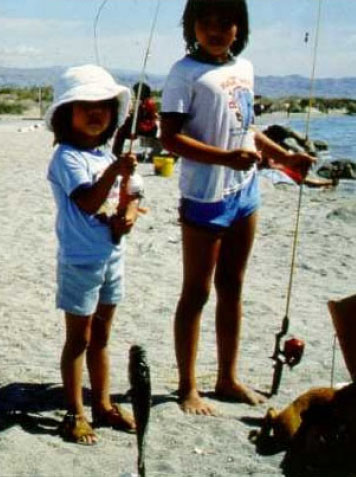 Two small children with fishing equipment on the beach at the Salton Sea