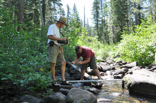 Two people collecting samples in a rocky stream