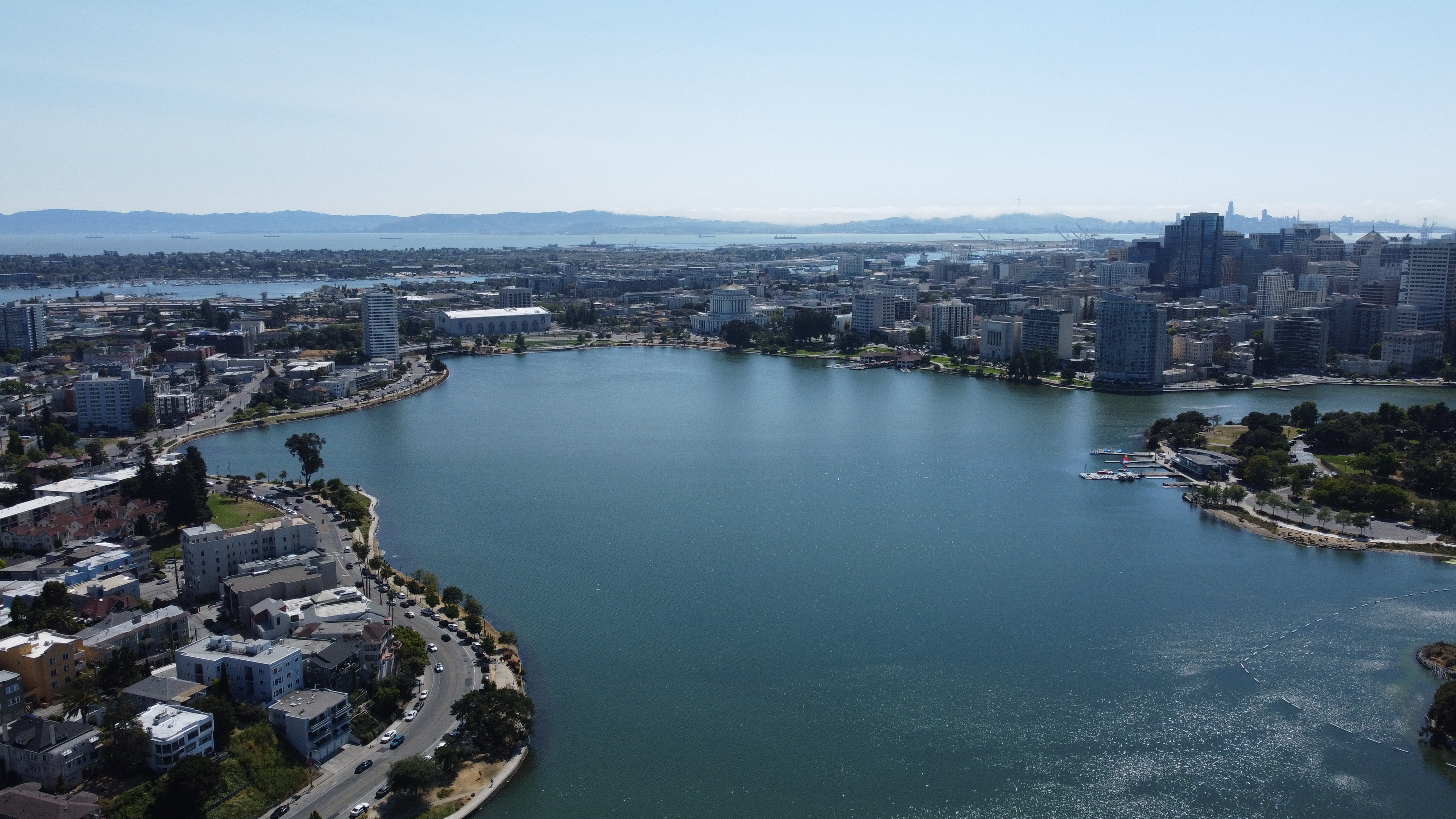 Aerial view of Lake Merritt taken from north side of lake using a drone, showing Oakland Harbor and portion of SF Bay in background.
