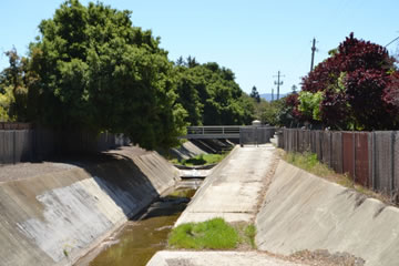 Photo of Permanente Creek before the diversion channel near Berry Ave. in Mountain View. The creek is flowing through a concrete trapezoidal channel at this location