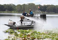 Man in boat spraying pesticides on weeds